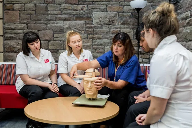 Photo showing leader using model of head in demonstration to students